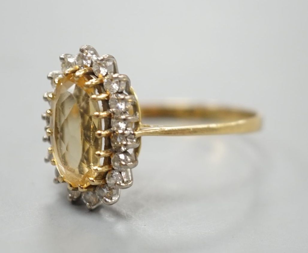 A modern yellow metal, yellow topaz and diamond set oval cluster ring, size T, gross weight 3.7 grams.